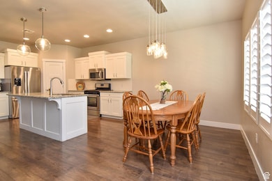 Dining area with dark wood-style flooring, recessed lighting, baseboards, and a chandelier