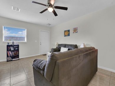 Living room featuring ceiling fan and light tile p