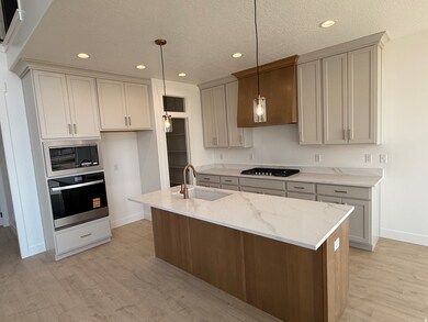 Kitchen featuring a kitchen island with sink, stainless steel appliances, a textured ceiling, light stone counters, and recessed lighting