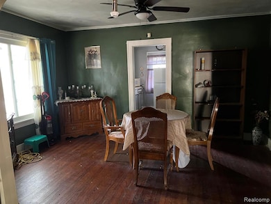 Dining area featuring dark wood-type flooring, crown molding, and ceiling fan
