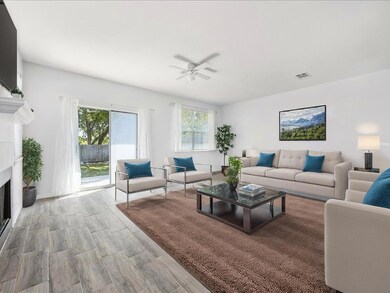 Living room featuring a fireplace, light wood-type flooring, and ceiling fan
