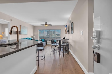 Kitchen featuring a ceiling fan, light wood finished floors, a kitchen bar, dark countertops, and open floor plan
