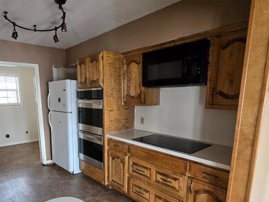 Kitchen with brown cabinetry, black appliances, li