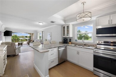 Kitchen featuring appliances with stainless steel finishes, crown molding, white cabinets, glass insert cabinets, and a peninsula