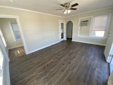 Empty room featuring ceiling fan, ornamental molding, dark wood-type flooring, and a wall unit AC