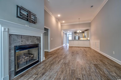 Unfurnished living room with dark wood finished floors, a tile fireplace, crown molding, a chandelier, and baseboards