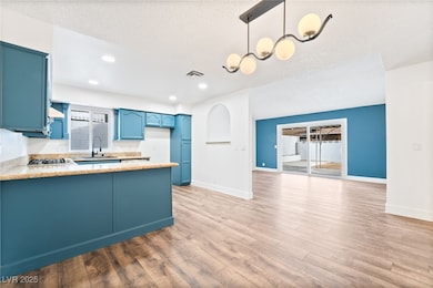 Kitchen featuring blue cabinets, a sink, a peninsu