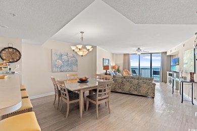 Dining room with expansive windows, light wood-style floors, a ceiling fan, a chandelier, and a textured ceiling