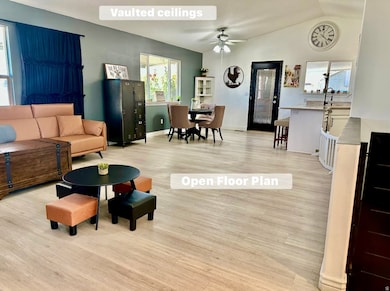 Living area featuring healthy amount of natural light, light wood-style flooring, ceiling fan, and lofted ceiling