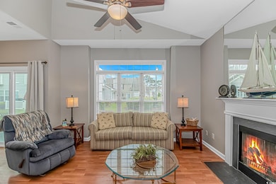 Living area with vaulted ceiling, ceiling fan, light wood-style floors, a fireplace, and baseboards