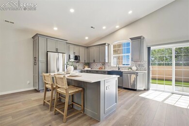 Kitchen with gray cabinets, appliances with stainless steel finishes, backsplash, lofted ceiling, and light wood-style flooring