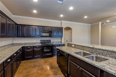 Kitchen featuring concrete flooring, recessed lighting, a sink, and black appliances