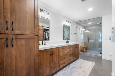 Bathroom with double vanity, a stall shower, recessed lighting, and a spacious closet