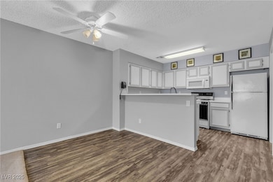 Kitchen with white appliances, dark wood-style flo