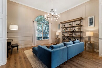 Living room with crown molding, an inviting chandelier, and LVP / wood-style floors