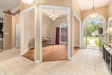 Entryway featuring light tile patterned floors, a chandelier, and a tray ceiling