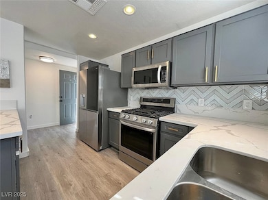 Kitchen with light stone counters, visible vents,