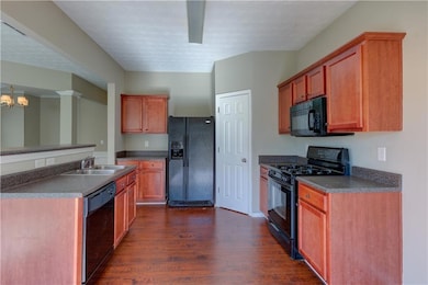 Kitchen with a textured ceiling, black appliances,
