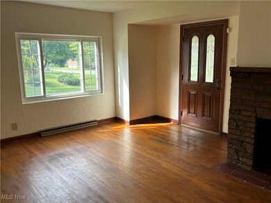 Entrance foyer with a stone fireplace, a baseboard heating unit, and wood-type flooring