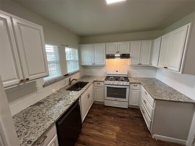 Kitchen featuring light stone counters, white range with gas cooktop, white cabinetry, and backsplash