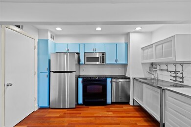 Kitchen with blue cabinetry, sink, light wood-type