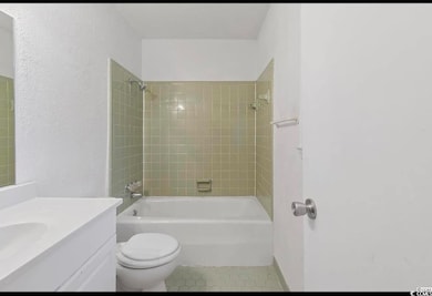 Bathroom featuring shower / washtub combination, vanity, tile patterned flooring, and a textured wall