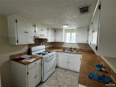Kitchen featuring white cabinetry, custom exhaust hood, and white gas range oven