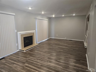 Unfurnished living room featuring a tile fireplace, dark wood-type flooring, and recessed lighting