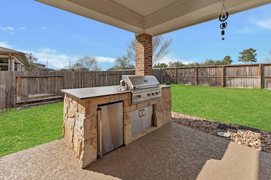 Outdoor kitchen with gas grill and refrigerator.