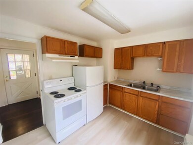 Kitchen featuring white appliances, brown cabinetry, light countertops, and light wood-style flooring