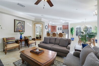 Living room with light tile patterned floors, ceiling fan with notable chandelier, and crown molding