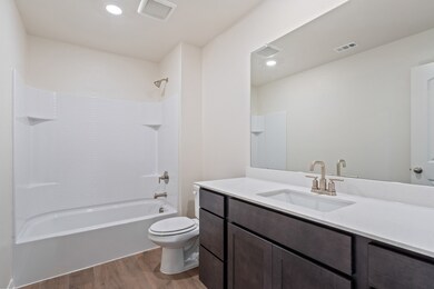 Bathroom with dark wood finished floors,  shower combination, vanity, and recessed lighting