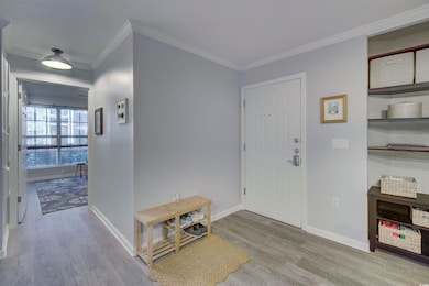 Foyer with crown molding and hardwood / wood-style