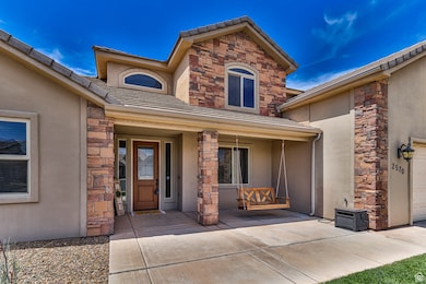 Property entrance with stone siding, stucco siding, and covered porch