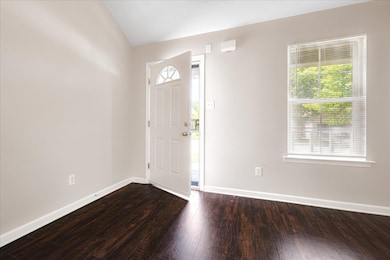 Entrance foyer featuring dark wood finished floors, vaulted ceiling, and baseboards