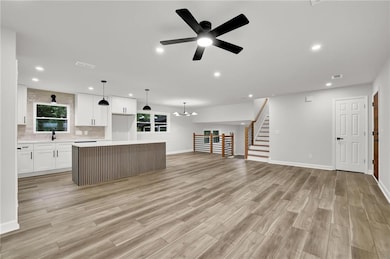 Kitchen featuring light wood finished floors, light countertops, recessed lighting, white cabinetry, and open floor plan