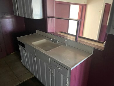 Kitchen with a sink, light countertops, and dark t