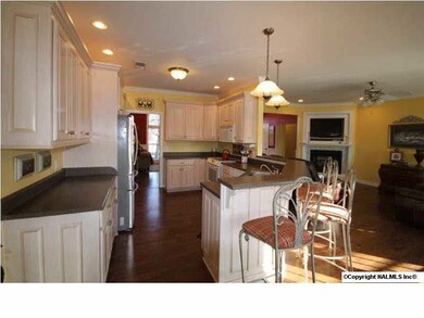 Open Kitchen has beautiful lighting, flooring and cabinetry! Plenty of cabinet and counter space and eat-at bar.