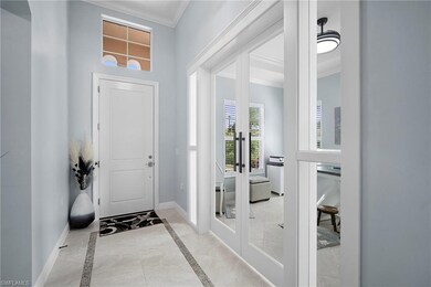 Entryway with french doors, ornamental molding, and inlaid floor details
