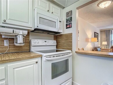 Kitchen with white appliances, a textured ceiling, and decorative backsplash
