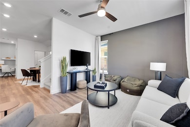 Living area featuring visible vents, ceiling fan, stairway, light wood-type flooring, and recessed lighting
