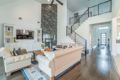 Living area featuring high vaulted ceiling, stairs, and wood finished floors
