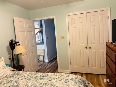Bedroom with wood finished floors, a closet, and baseboards