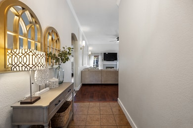 Hallway featuring light tile patterned floors, a textured wall, and arched walkways