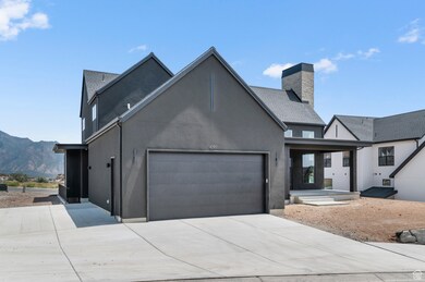 View of front of home featuring a garage, stucco siding, concrete driveway, a chimney, and a mountain view