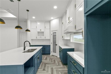 Kitchen with light parquet floors, refrigerator, blue cabinetry, decorative light fixtures, and white cabinetry