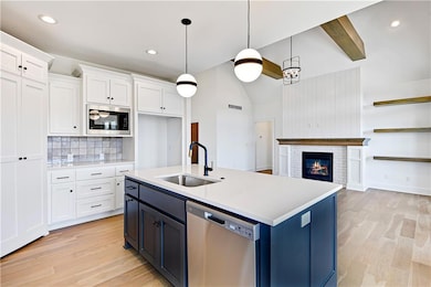 Kitchen featuring white cabinetry, a sink, light wood finished floors, and appliances with stainless steel finishes