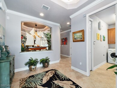 Hallway with washer / dryer, ornamental molding, a tray ceiling, and visible vents