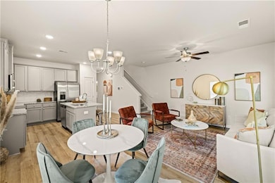 Dining area with stairway, a ceiling fan, light wood finished floors, recessed lighting, and a chandelier