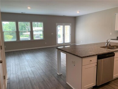 Kitchen featuring stainless steel dishwasher, white cabinetry, dark wood-type flooring, dark stone counters, and recessed lighting